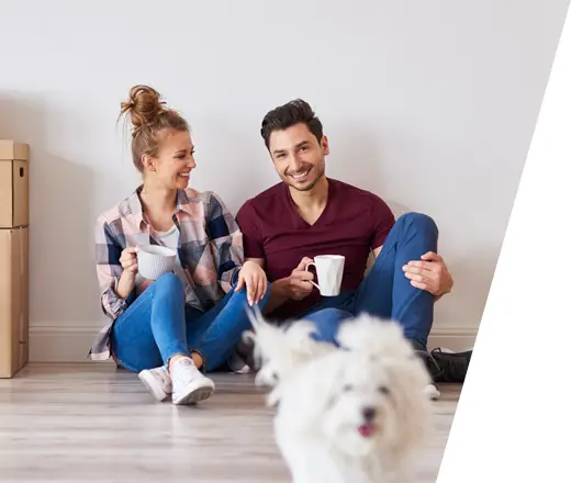 happy male and female sitting on the floor drinking a cup of coffee with their dog