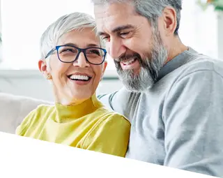 senior male and female sitting on a couch using an iPad